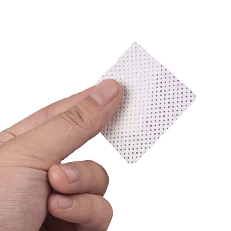 a hand holding a single quilted wipe on a white background