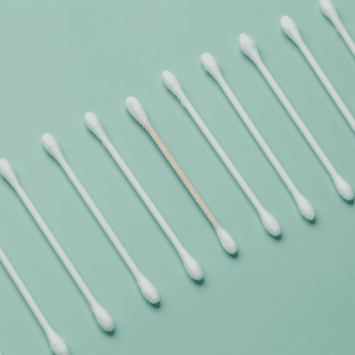 White cotton swabs lined up on green background.