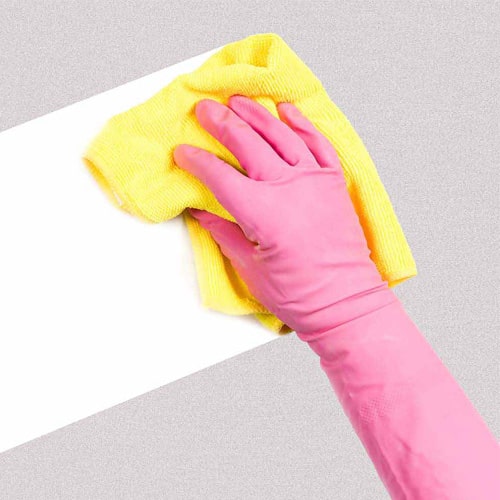 A person wearing pink gloves cleaning a countertop using a yellow cloth